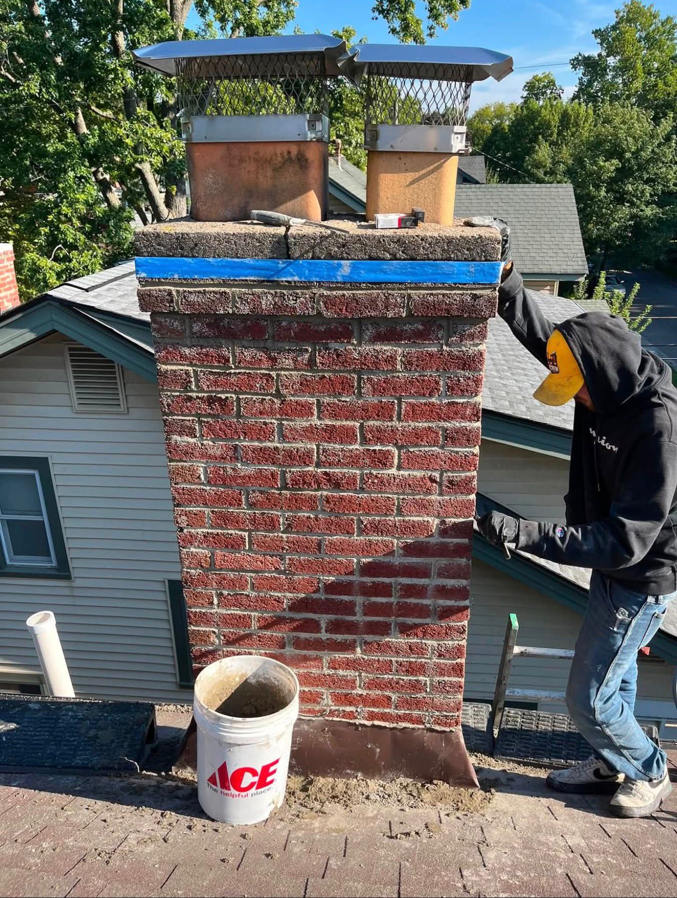 American Chimney & Masonry technician rebuilding a brick chimney crown on a rooftop