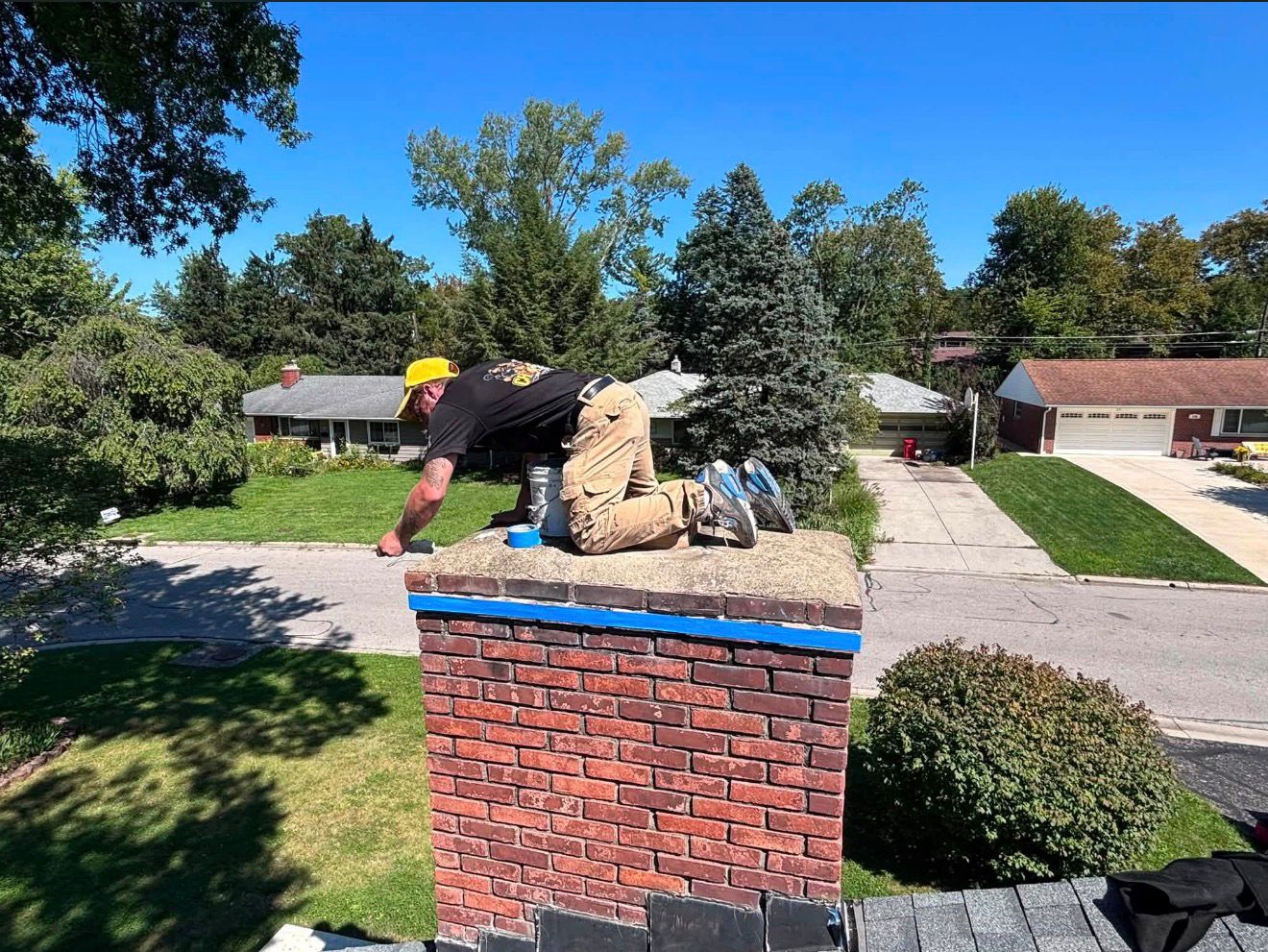 American Chimney & Masonry technician sealing a chimney crown on a Cincinnati rooftop