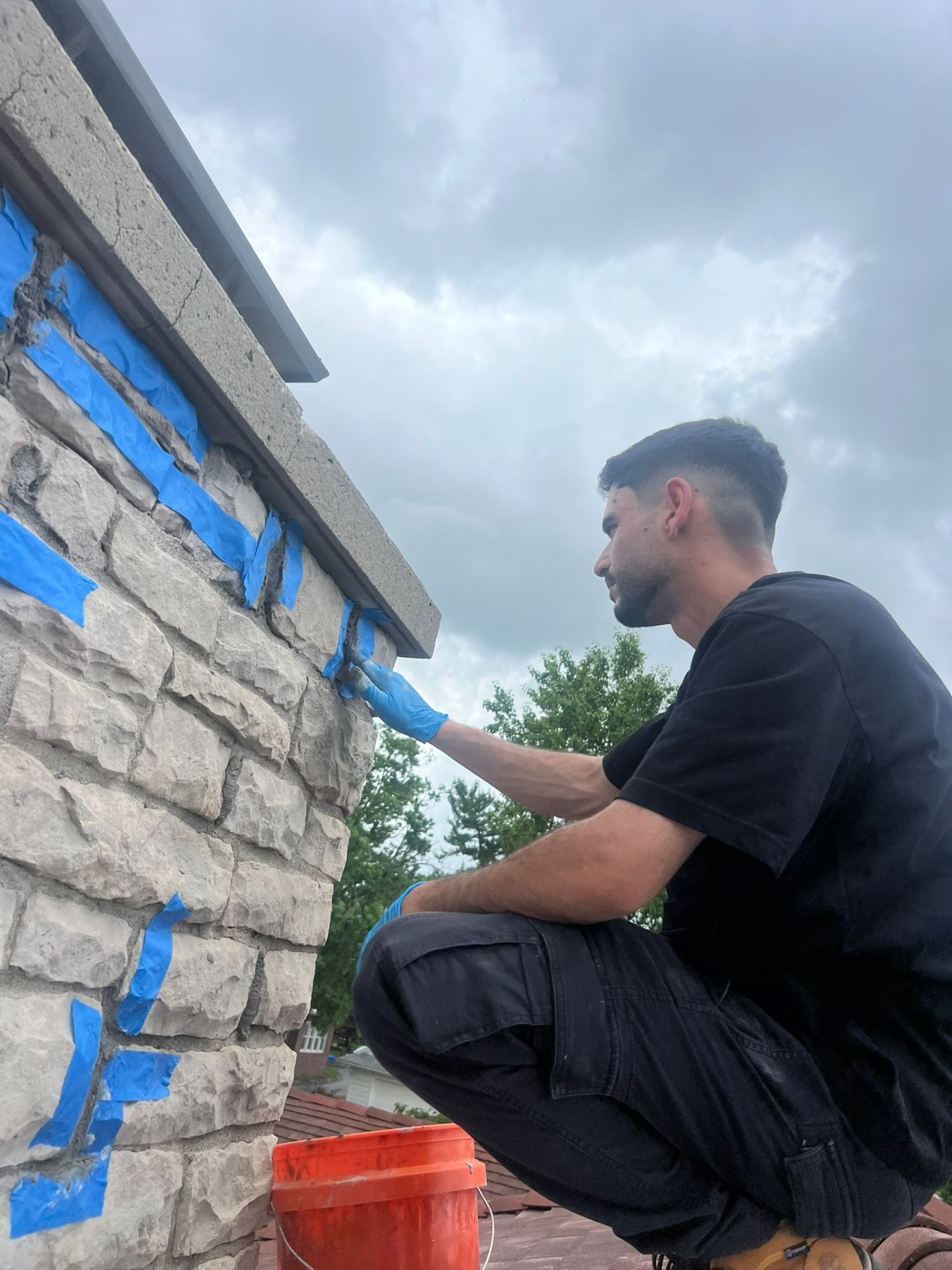 Technician tuckpointing mortar joints on a stone chimney