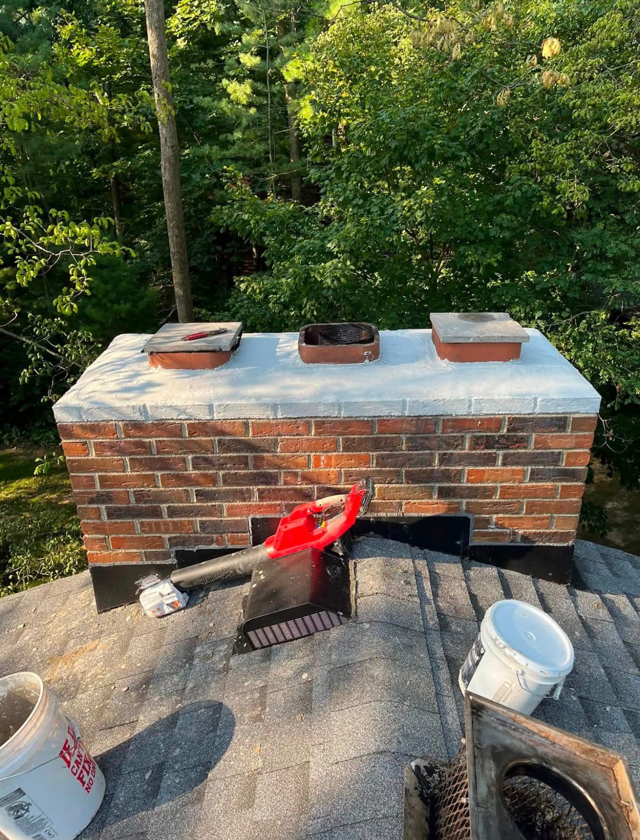 Freshly sealed chimney crown with new flashing on a shingled roof