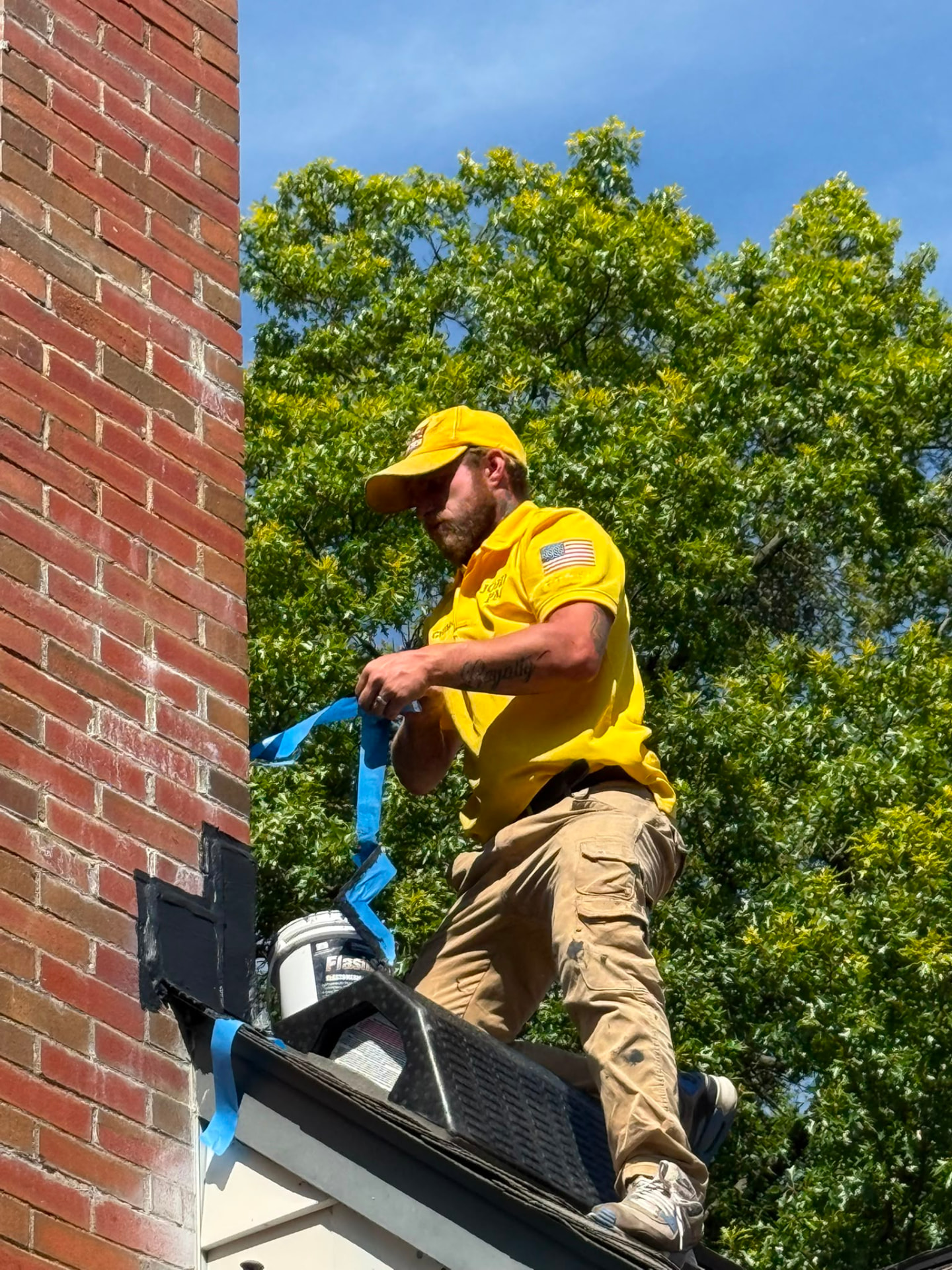 Chimney technician in American Chimney & Masonry uniform working beside a brick chimney