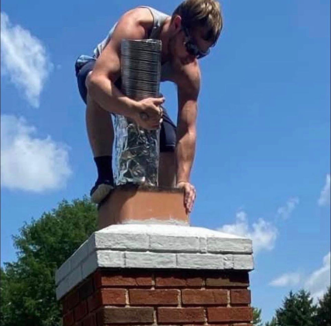 Technician feeding a stainless steel flexible liner into the flue from the chimney top