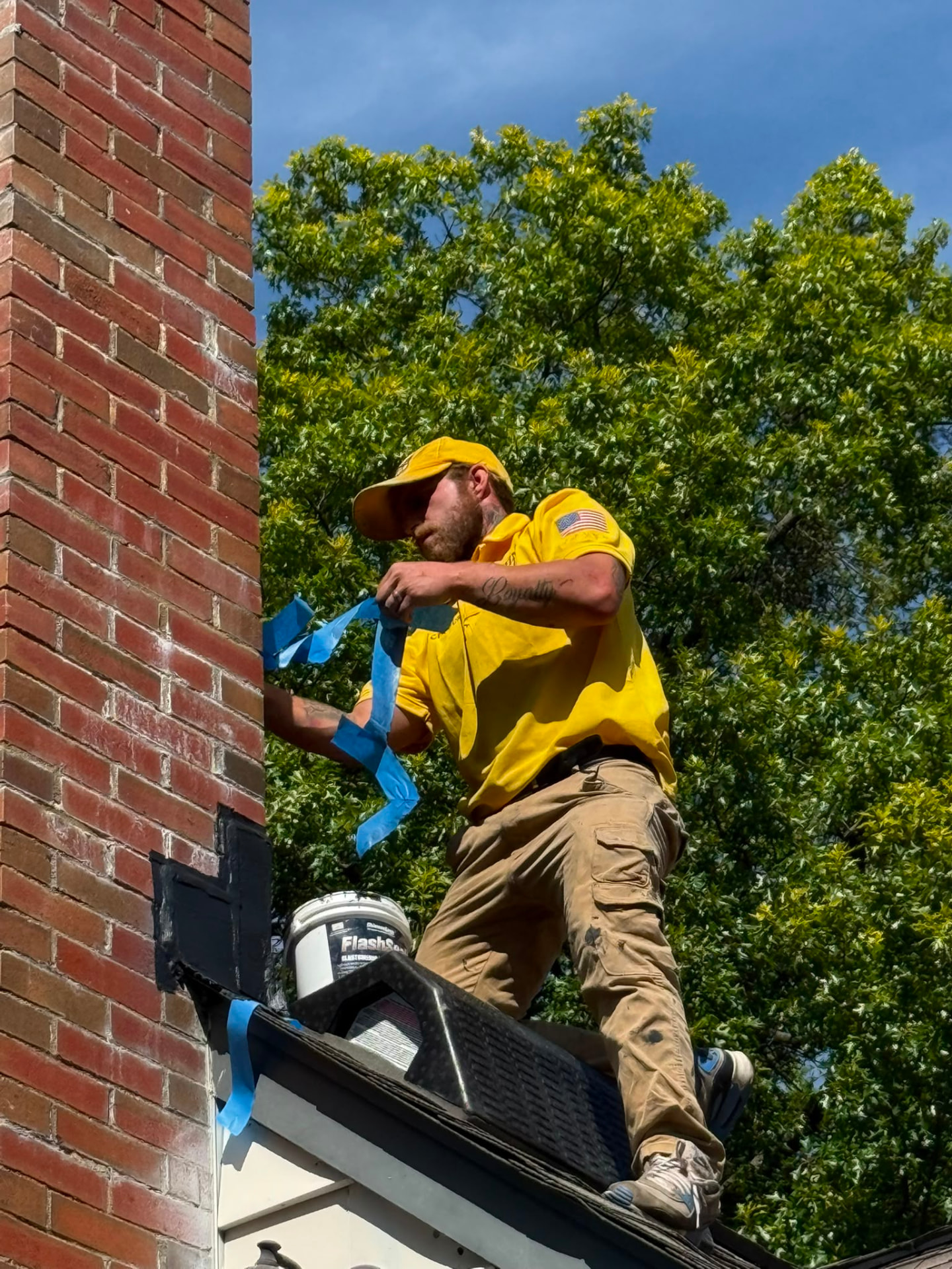 Technician removing masking tape after sealing chimney flashing