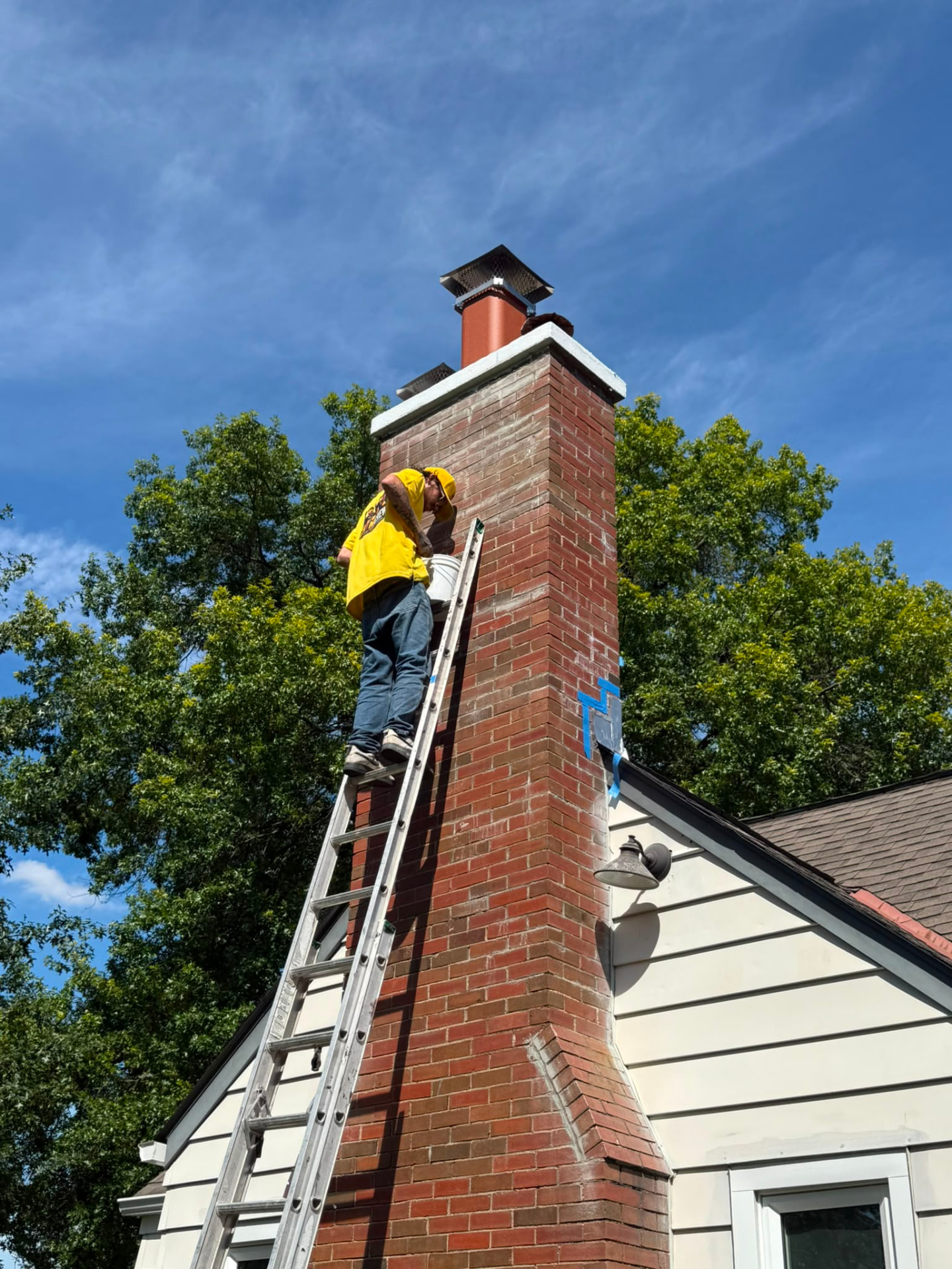 American Chimney & Masonry technician on a ladder working on a brick chimney in Cincinnati, Ohio
